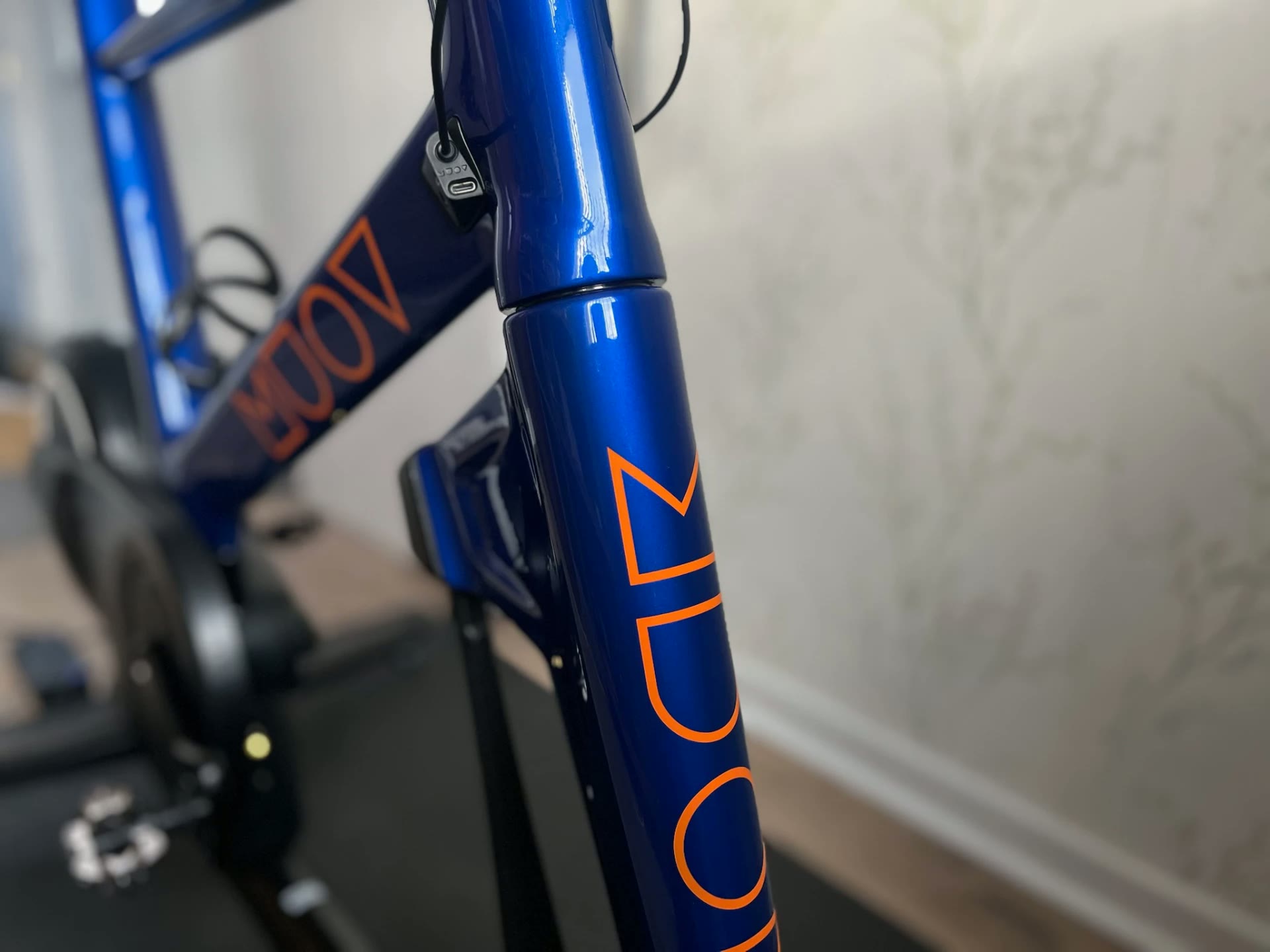 Close view of a deep blue MUOV frame with orange MUOV lettering along the fork