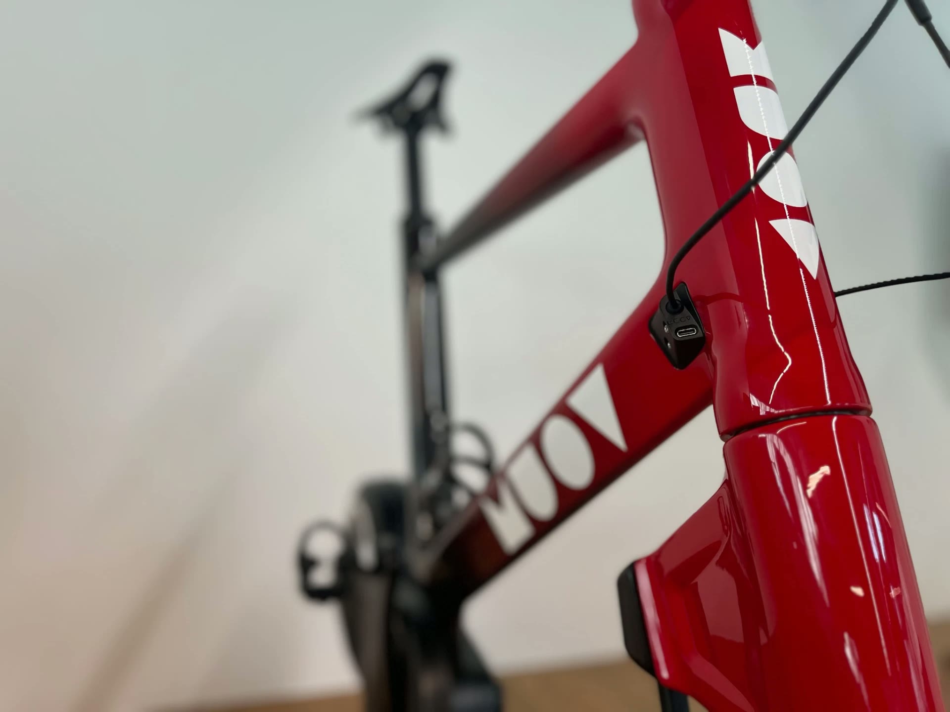 Close view of a red MUOV frame with white lettering and the charging port on the head tube