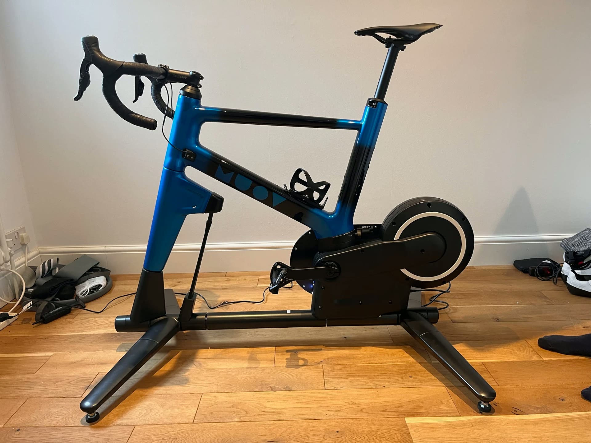 MUOV bike with a blue frame fading into black, on a wooden floor in a home room