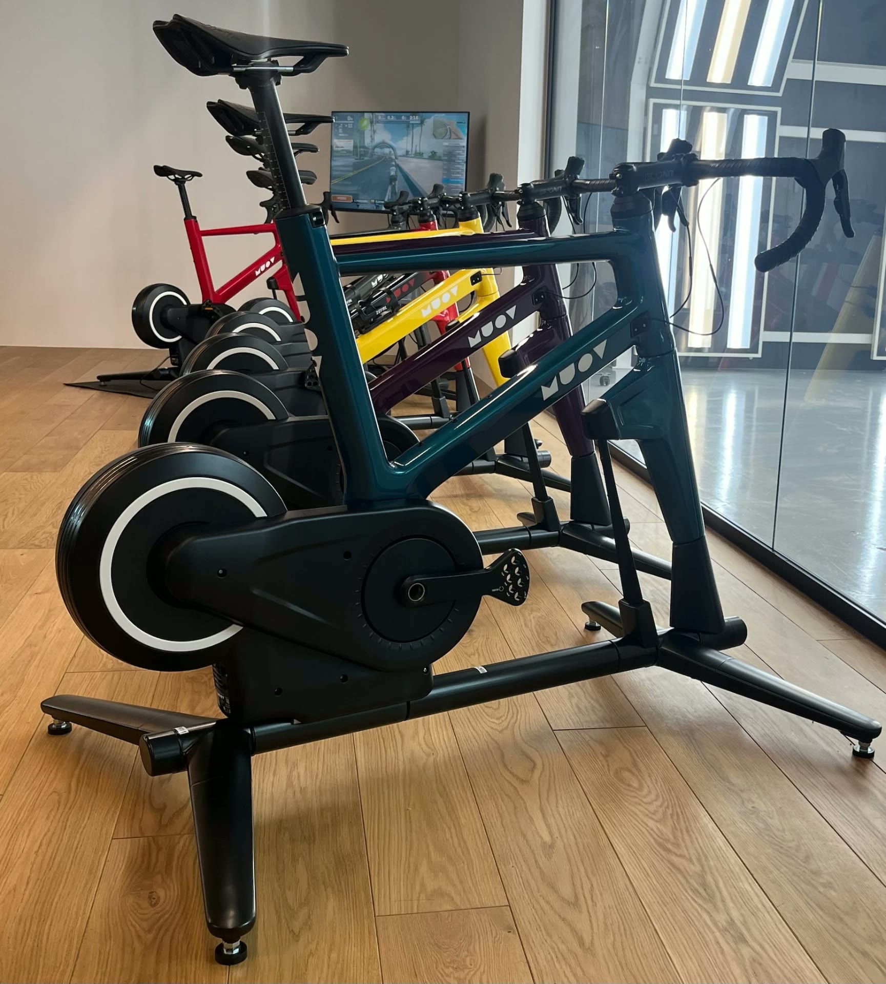 MUOV bike with a deep green frame in the foreground and red, yellow and purple MUOV bikes behind