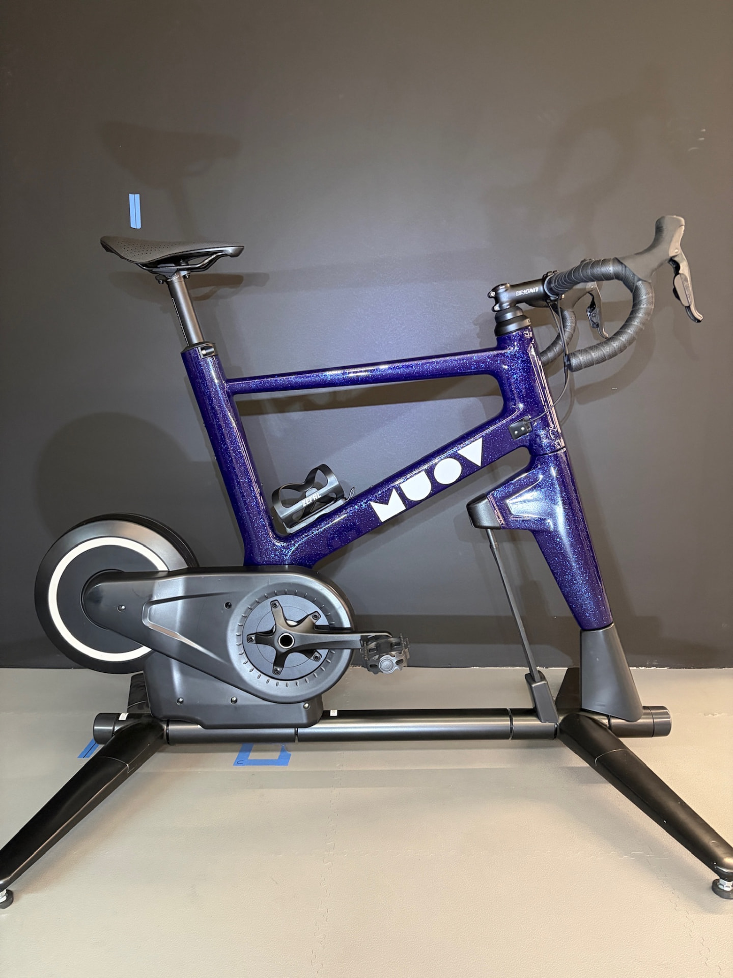 MUOV bike with a deep sparkling purple frame and white MUOV lettering, photographed side-on against a grey wall